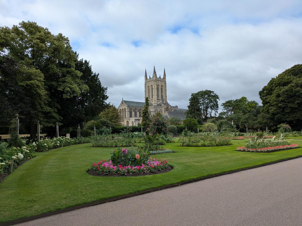 St Edmundsbury Cathedral and its pale stone tower seen across the lawns and flower beds of the Abbey Gardens