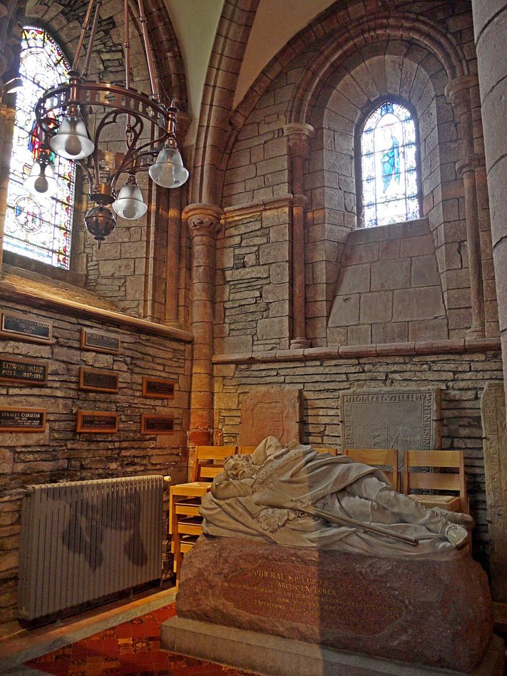 The carved stone memorial of the Arctic explorer John Rae, shown lying asleep with a book and rifle, in St Magnus Cathedral