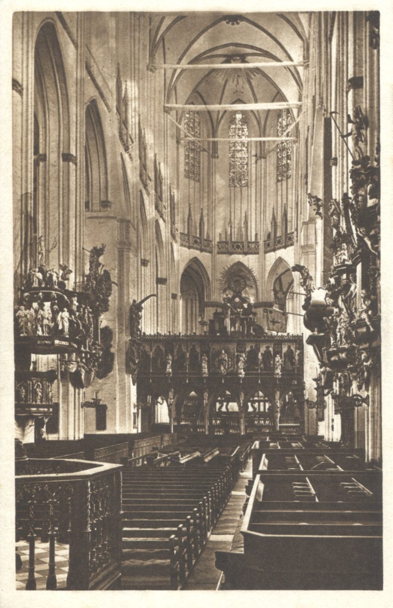 Old black-and-white photograph of the nave of St Mary's Church, Lübeck, crowded with Baroque fittings and a rood screen