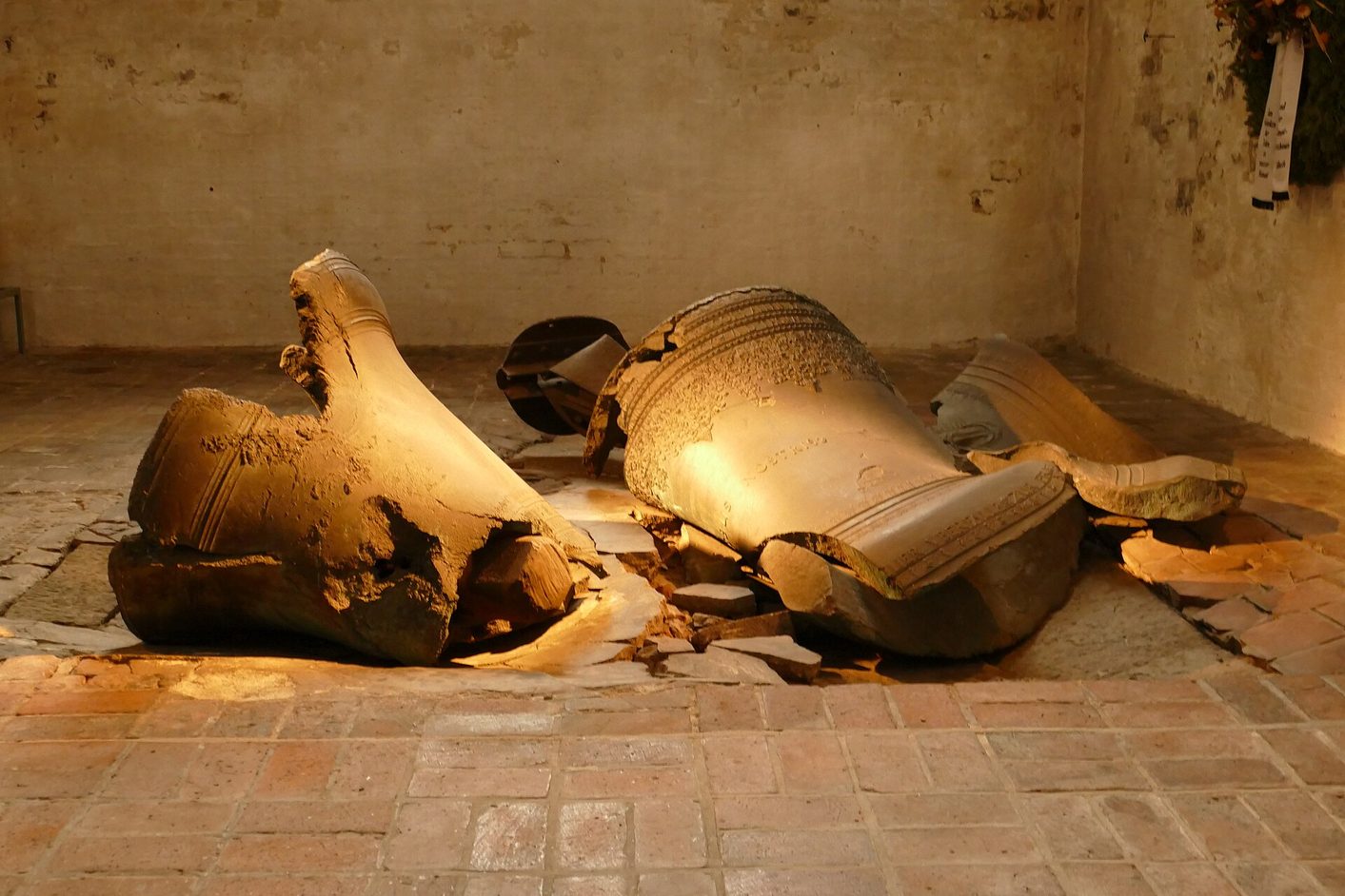 Two broken bronze church bells lying on the cracked brick floor of the south tower chapel of St Mary's, Lübeck