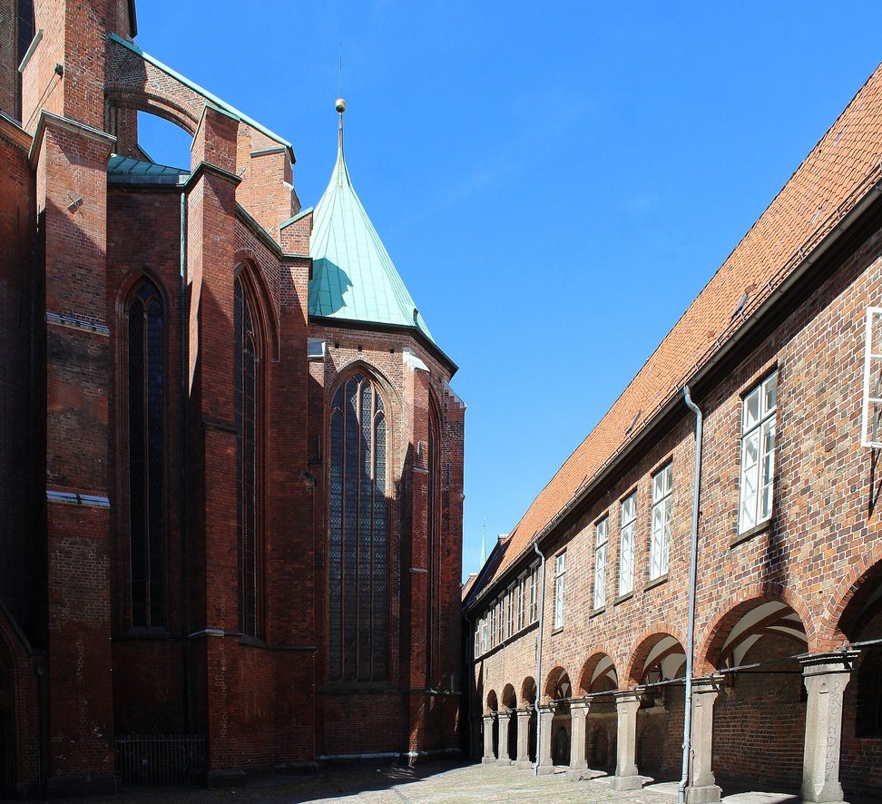 The red-brick flank of St Mary's Church in Lübeck beside the arcades of the old buildings on the Marienkirchhof