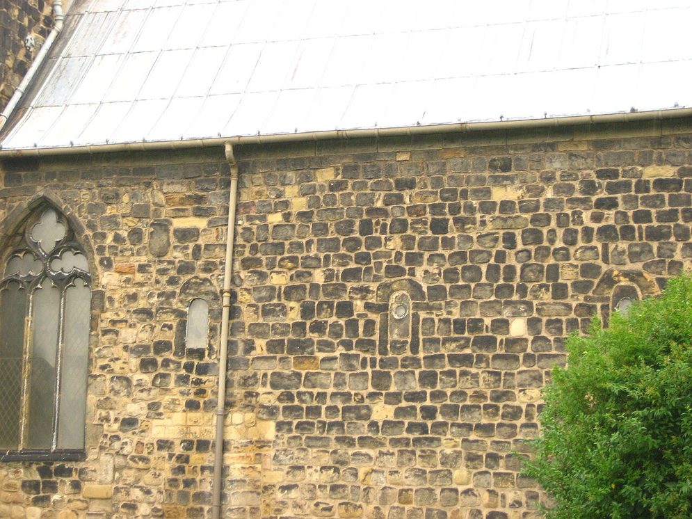 Small round-headed Anglo-Saxon windows set high in the rubble stone wall of the chancel at Jarrow