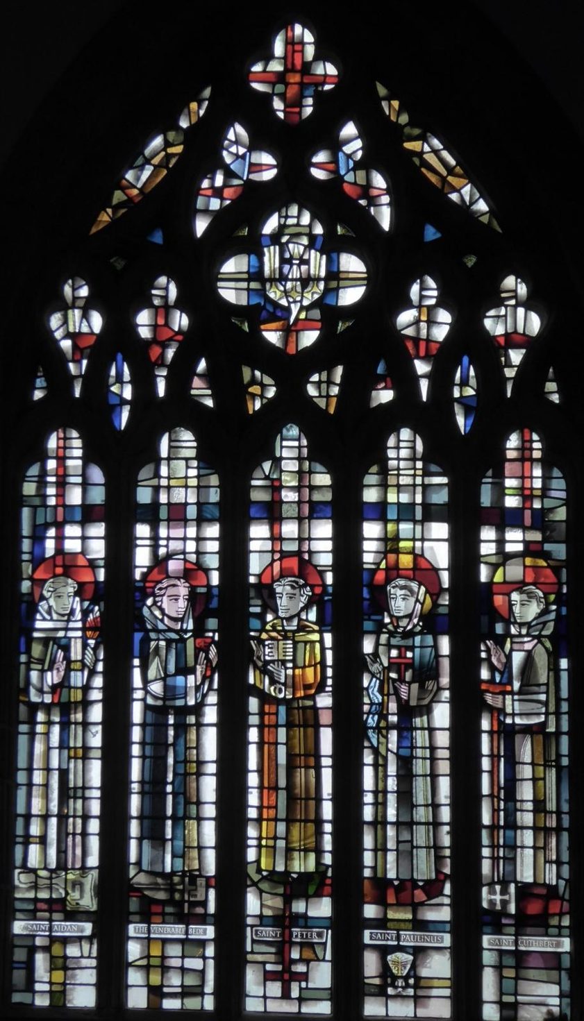 The east window of St Peter's Church, Monkwearmouth, tall lancets of stained glass with figures under bright tracery