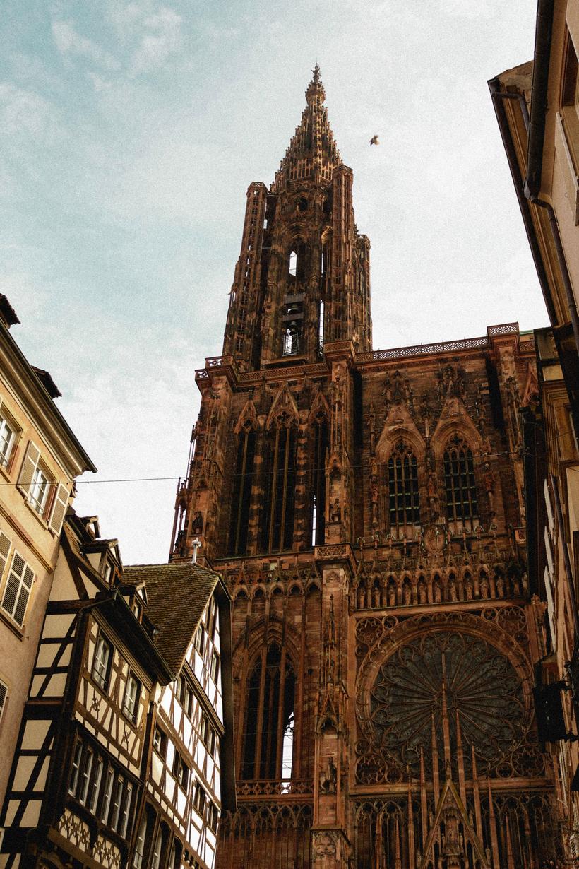 The single spire of Strasbourg Cathedral rising at the end of a narrow street of old houses