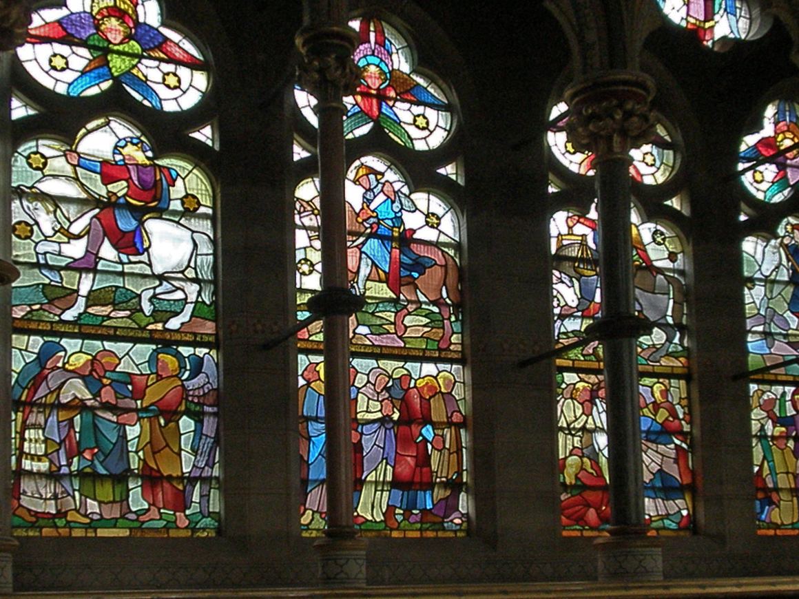 A row of stained-glass windows at St Mary's, Studley Royal, showing horsemen of the Apocalypse above crowds of figures
