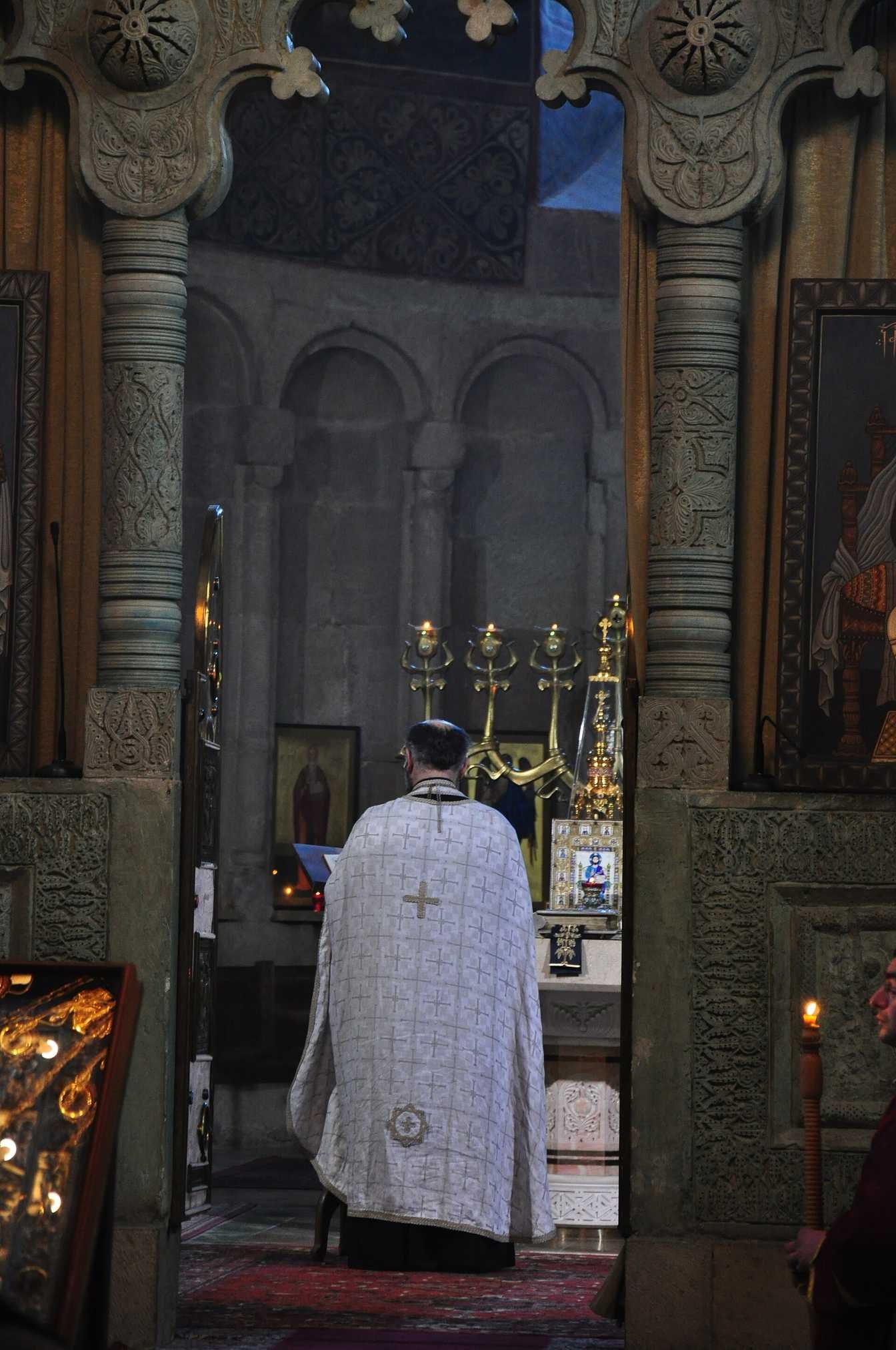 A woman praying by candlelight inside Svetitskhoveli Cathedral