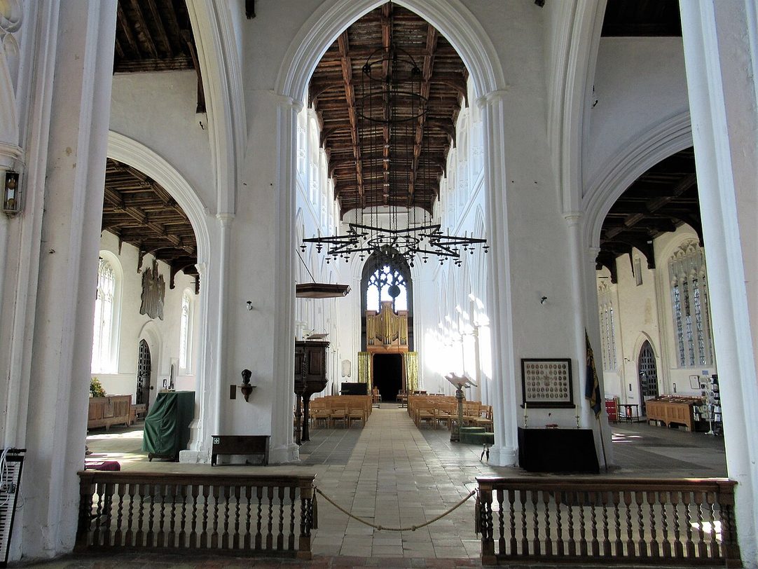 Looking west through the wide interior of Thaxted church, with chairs, arcades and the west tower arch