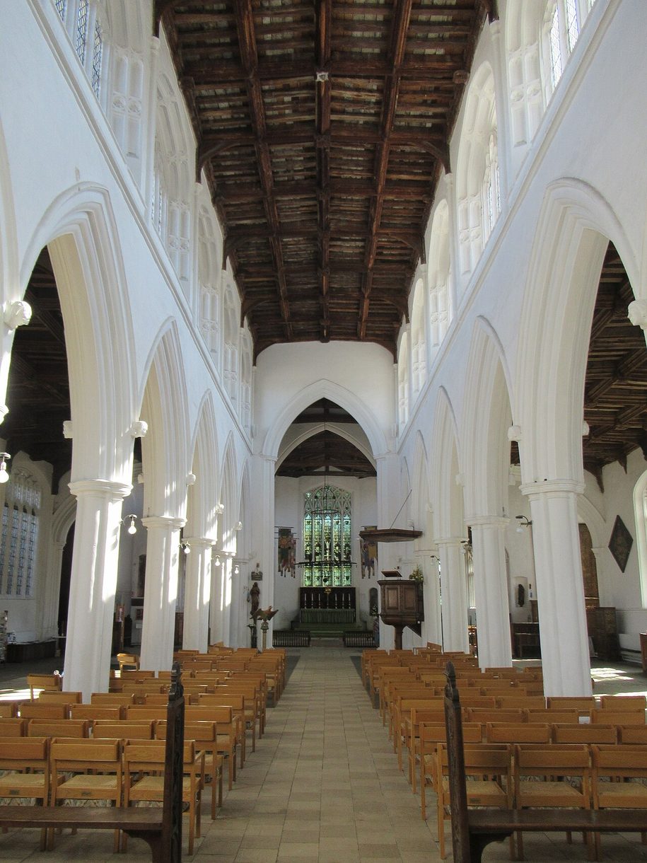 The light, white-walled nave of Thaxted church looking east, with tall arcades and a dark timber roof