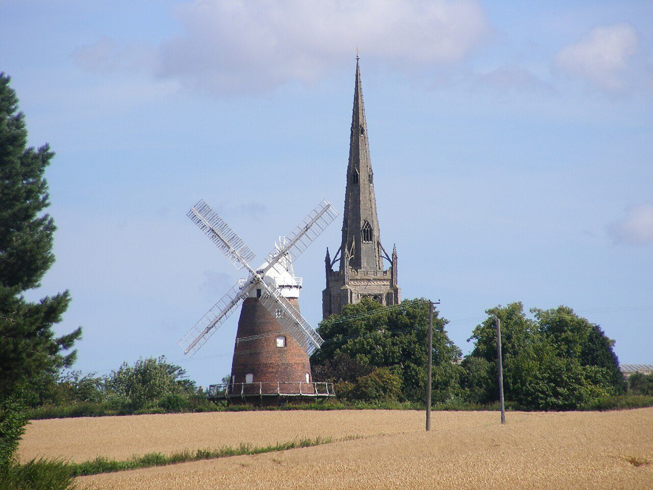 Thaxted's brick tower windmill and the church spire rising above a field
