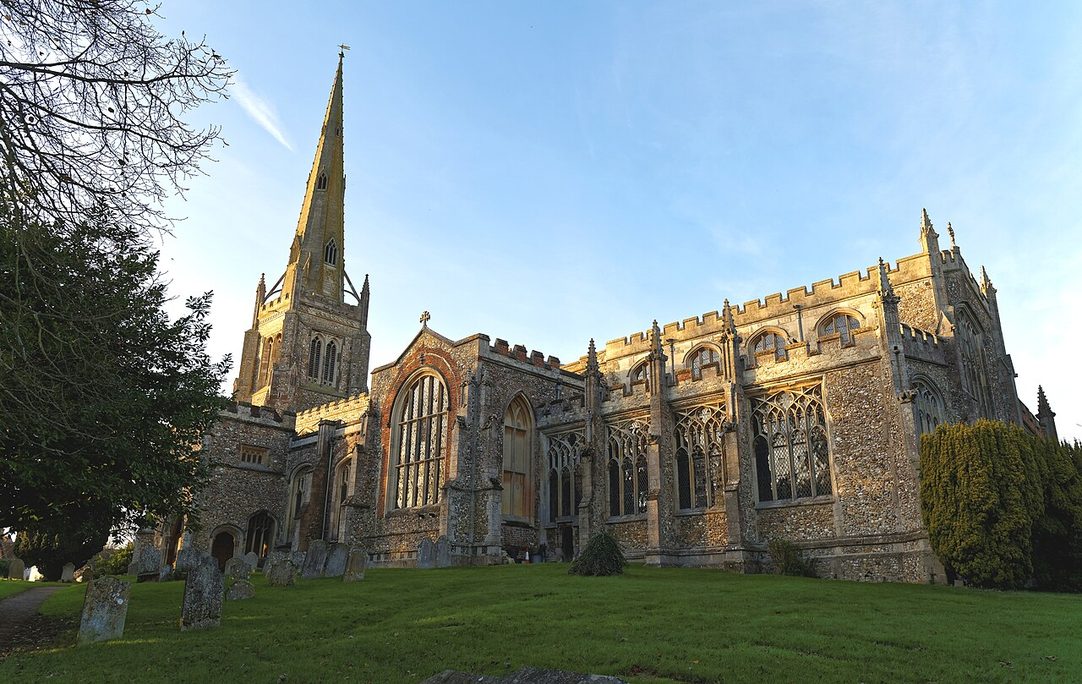 Thaxted parish church, Essex, seen from the south-east across the churchyard, with its tall spire and battlemented aisles