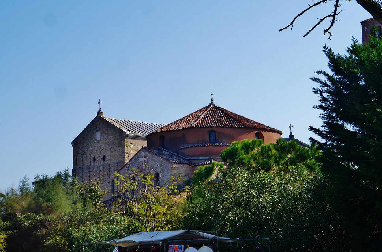 The brick basilica of Santa Maria Assunta and the round church of Santa Fosca among trees on the island of Torcello
