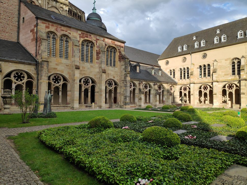 The garden of the Gothic cloister of Trier Cathedral, with arcades and the walls of the cathedral behind