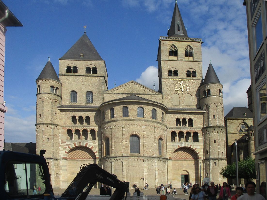 The Romanesque west front of Trier Cathedral, with its apse, two square towers and stair turrets, rising above the Domfreihof square
