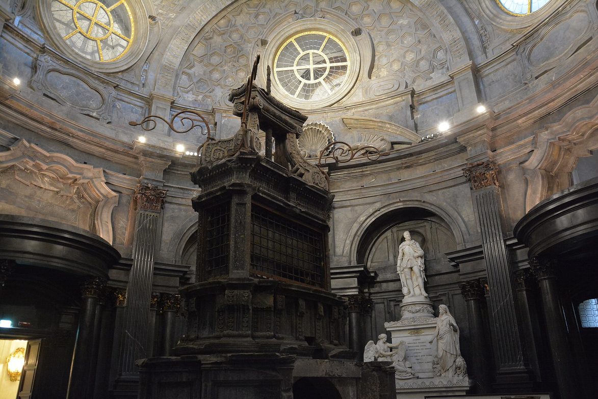 The dark marble interior of the Chapel of the Holy Shroud in Turin with the black Baroque altar and white marble tombs