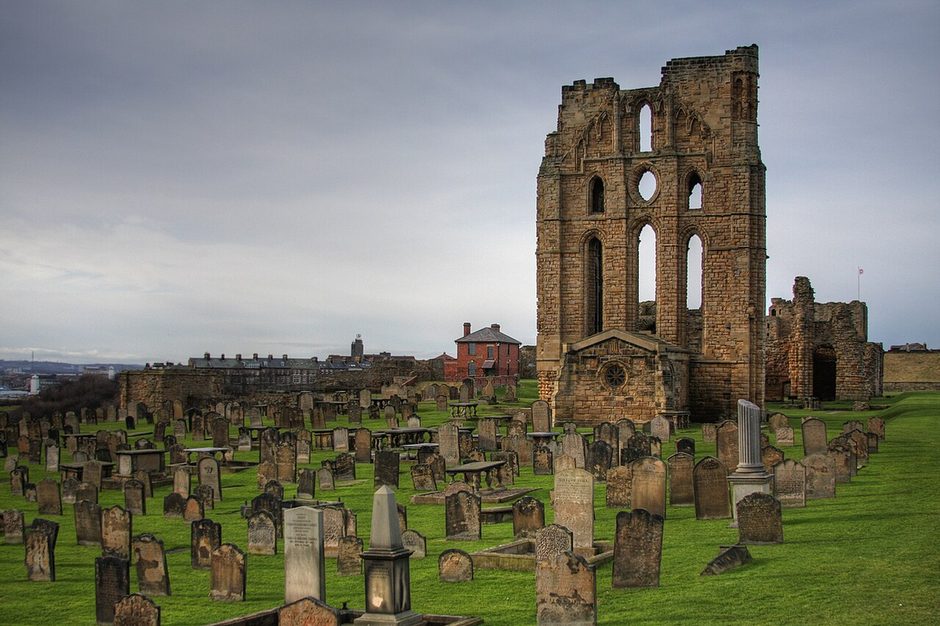 The tall ruined east end of Tynemouth Priory church rising above the gravestones of the headland churchyard
