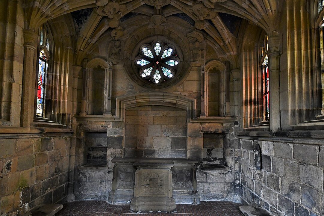 Inside the small vaulted Percy Chantry at Tynemouth Priory, with a rose window above the altar