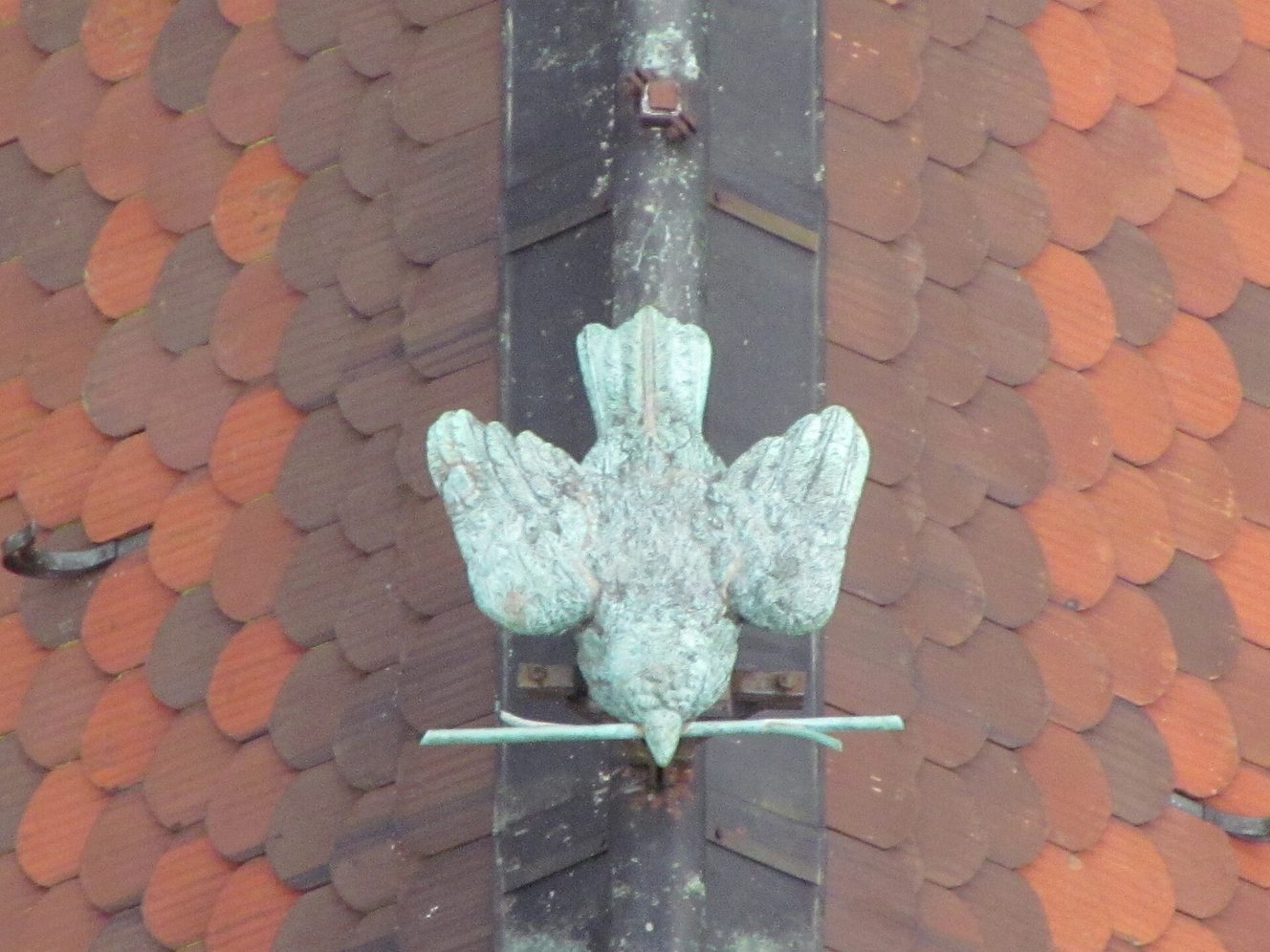A metal figure of a sparrow holding a straw on the roof ridge of Ulm Minster