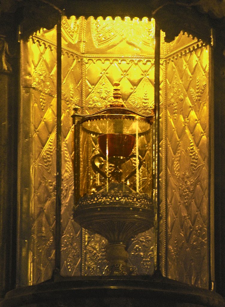 The Holy Chalice of Valencia, an agate cup on a gold stem and base, displayed in a glowing golden case