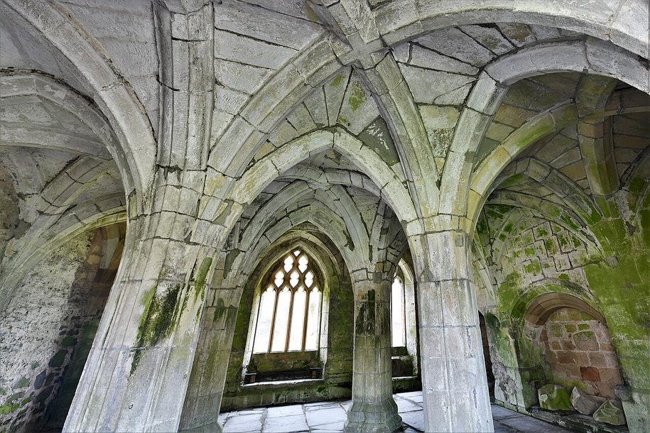 The rib-vaulted chapter house of Valle Crucis Abbey, with its pillars and stone floor