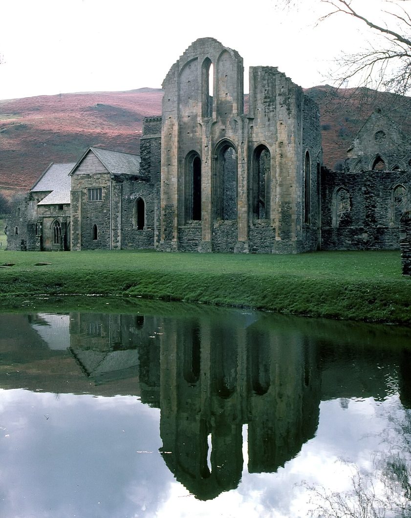 The east end of Valle Crucis Abbey reflected in the still water of the monastic fishpond