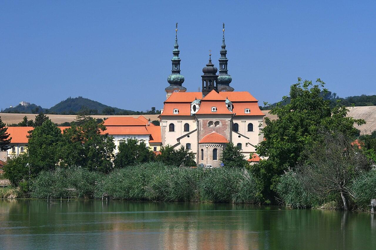 The Velehrad basilica seen across a pond with wooded hills behind