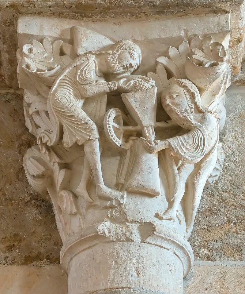 A carved Romanesque capital in the nave of Vézelay with lively figures among foliage