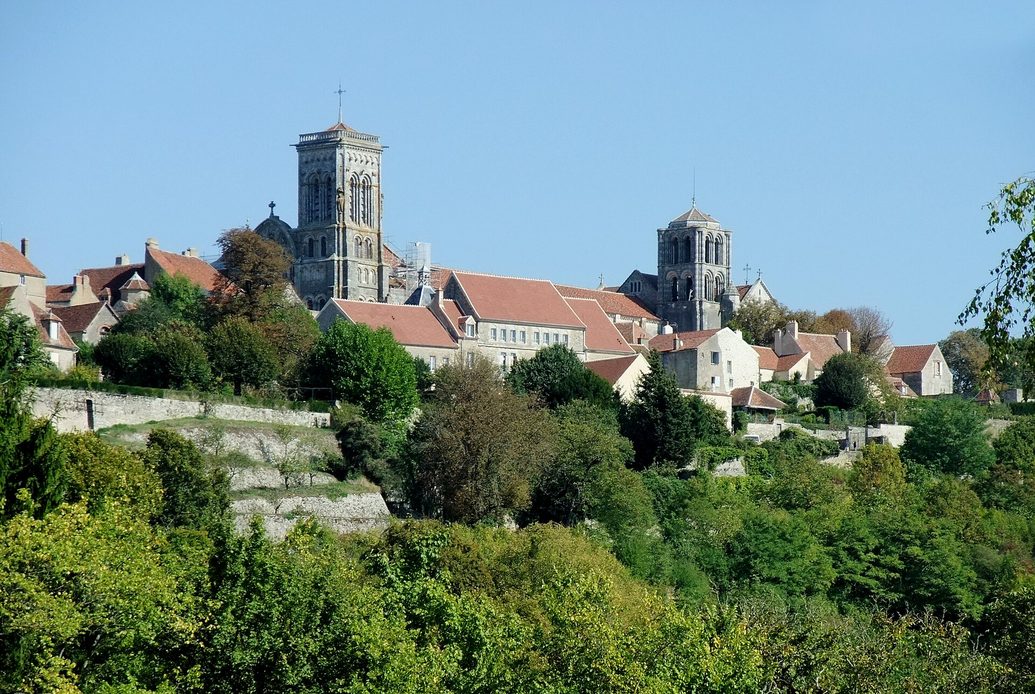 The Romanesque basilica of Vézelay with its tall square tower on top of the hill, above the village roofs and green Burgundian countryside