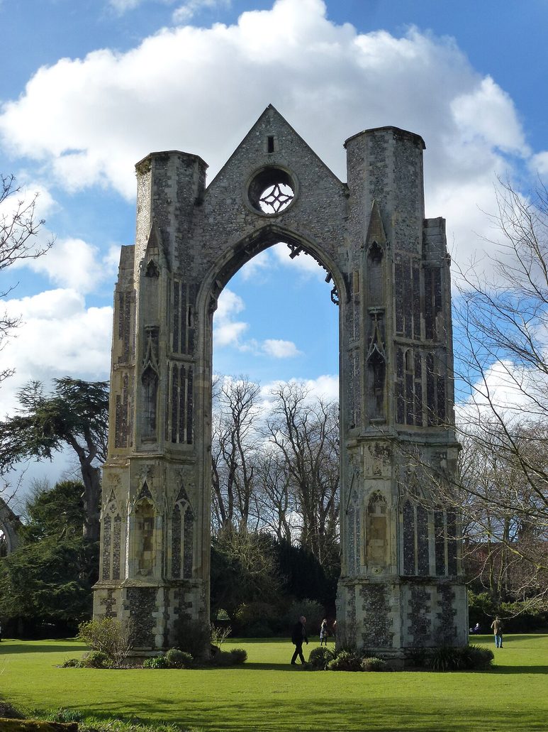 Close view of the ruined east window arch of Walsingham Priory, two flint and stone towers joined by a pointed arch
