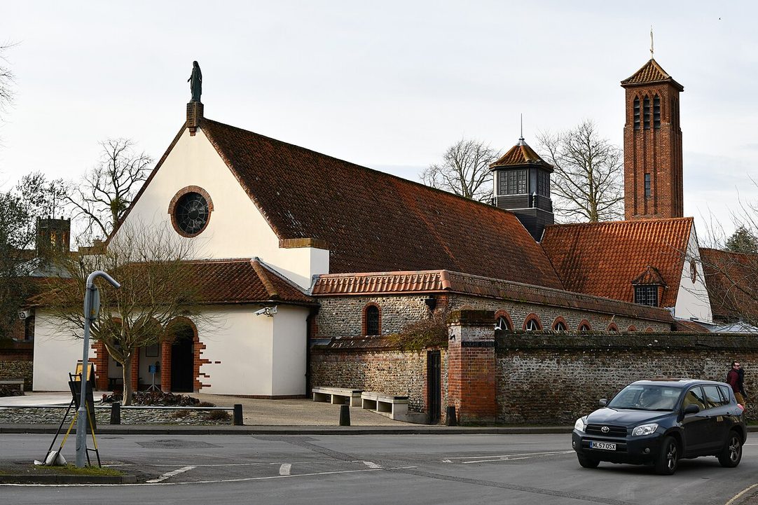 The Anglican Shrine Church of Our Lady of Walsingham, a brick and flint church with a tall tower, from the road