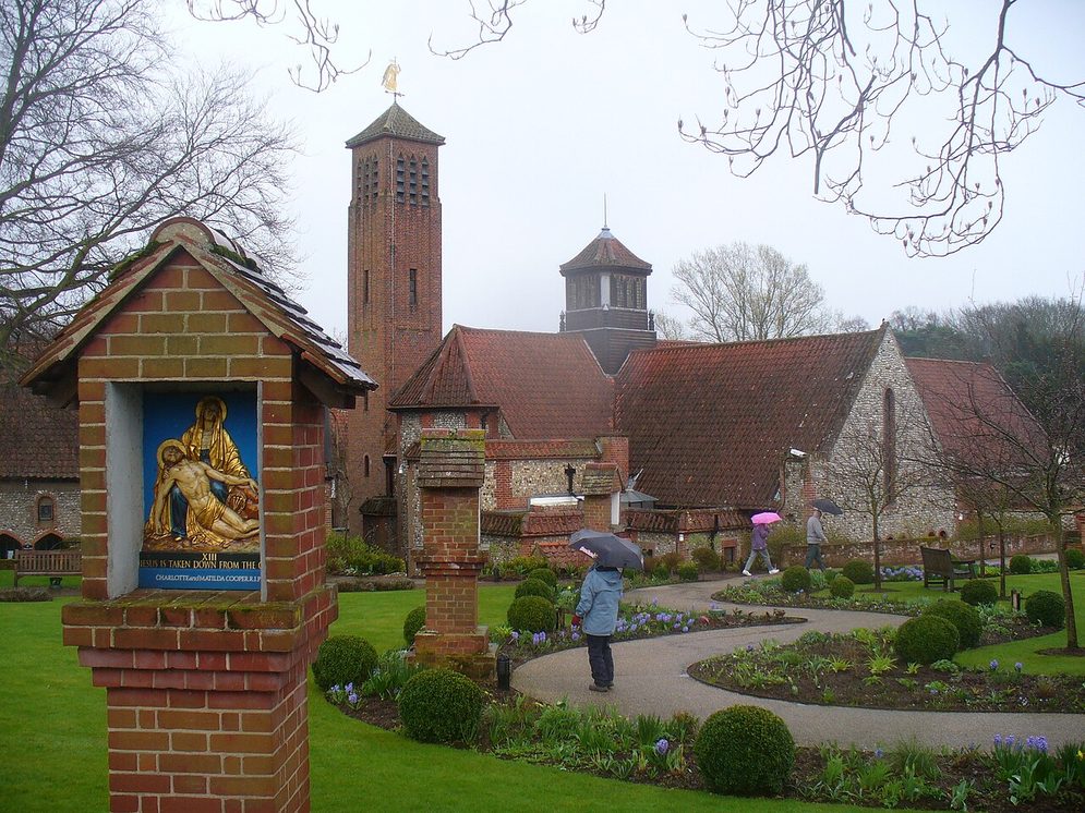 The garden of the Anglican shrine at Walsingham with a small wayside shrine and the shrine church behind