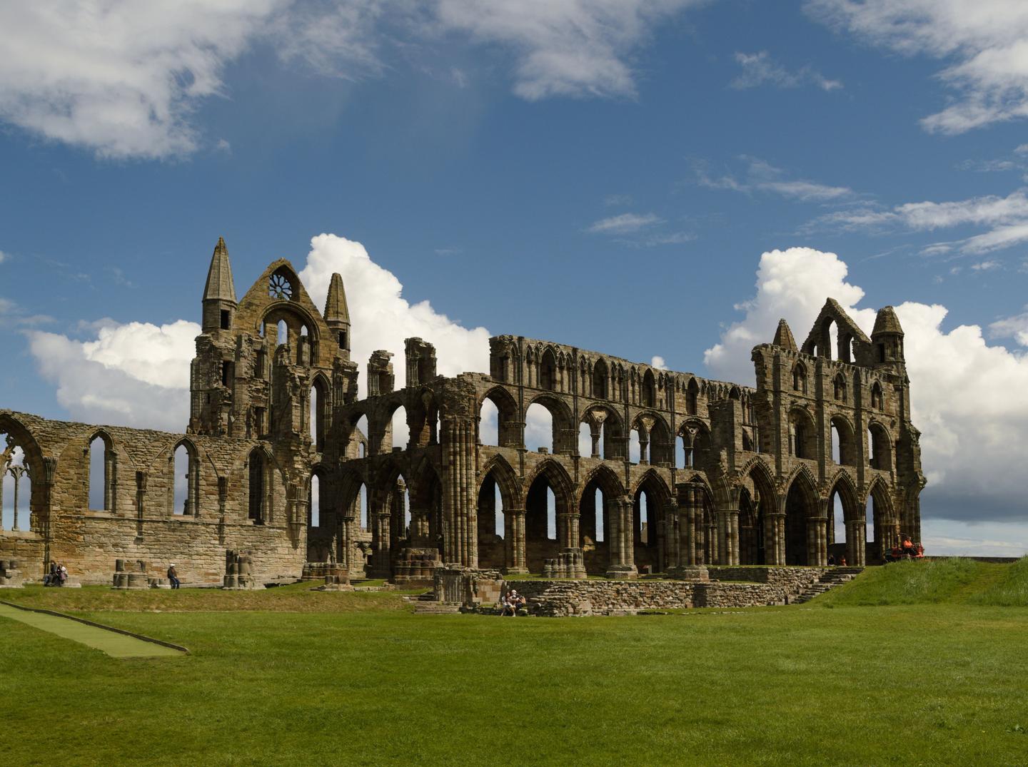 The ruined Gothic church of Whitby Abbey on its grassy clifftop under a blue sky