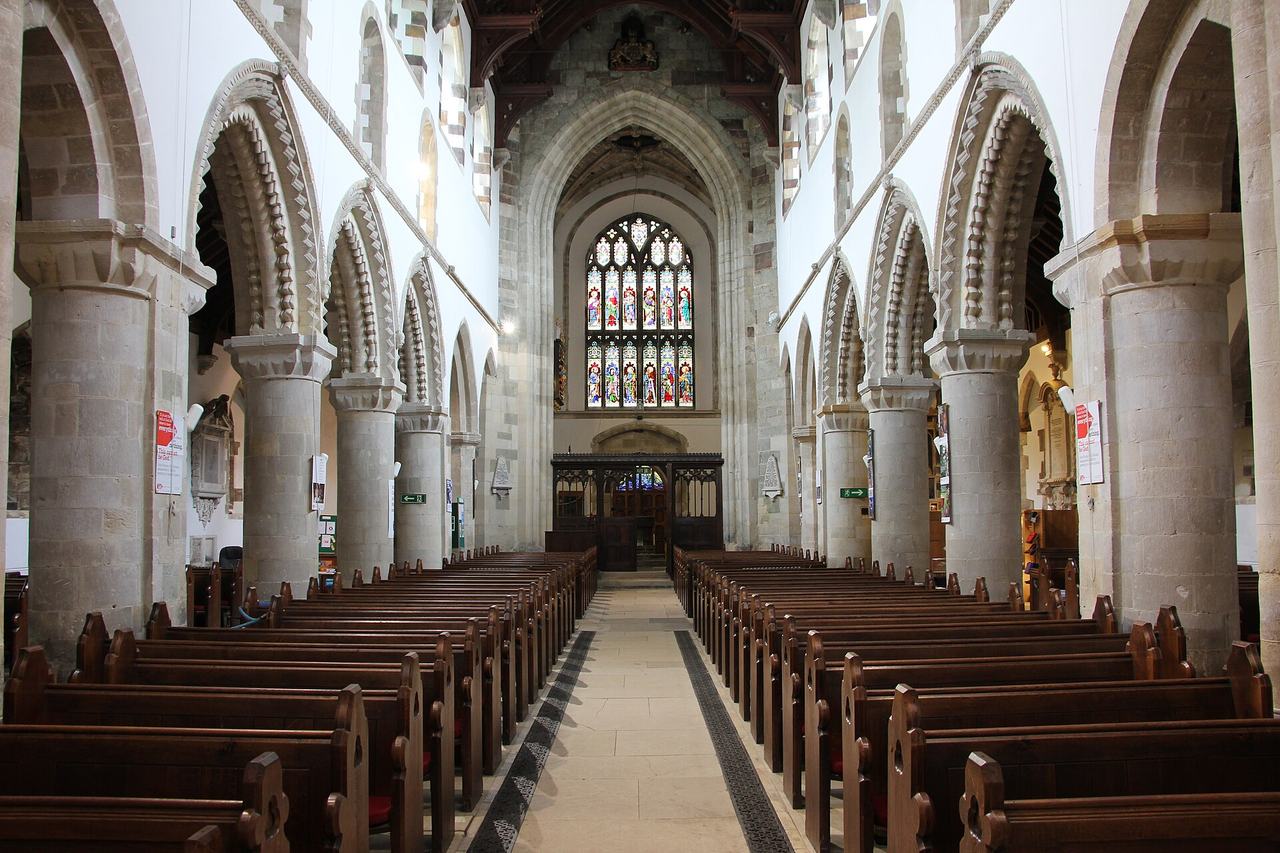 The nave of Wimborne Minster looking east, with round Norman arches and pews