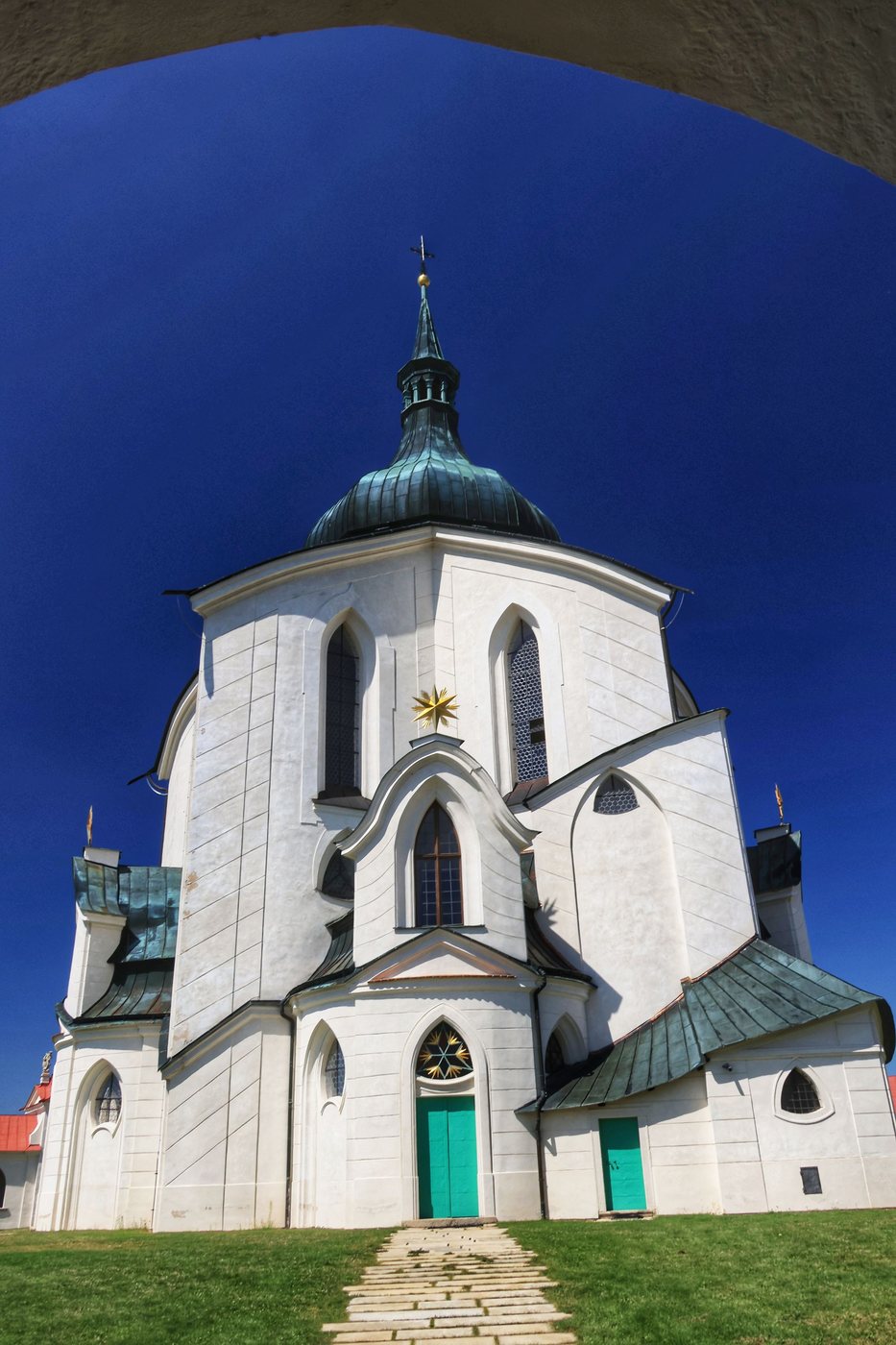 The white walls, pointed windows and green domed roof of the Zelená Hora church